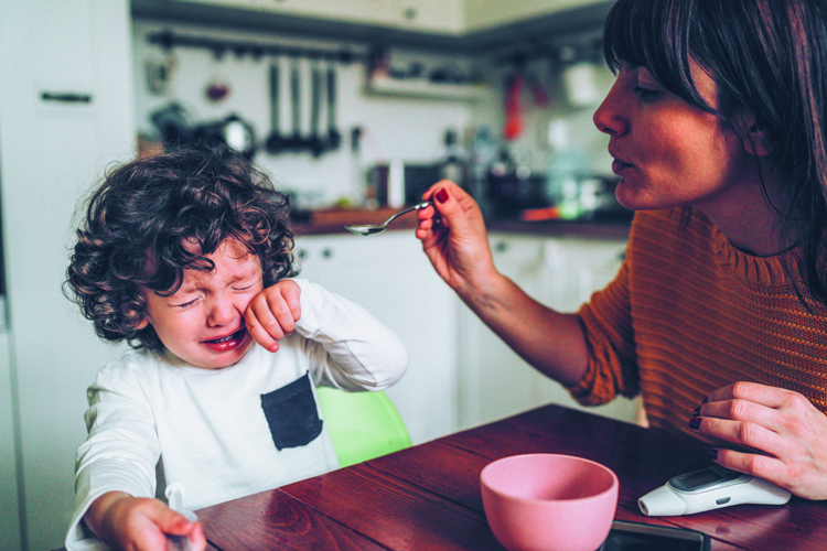 Young child taking medicine with adult assistance
