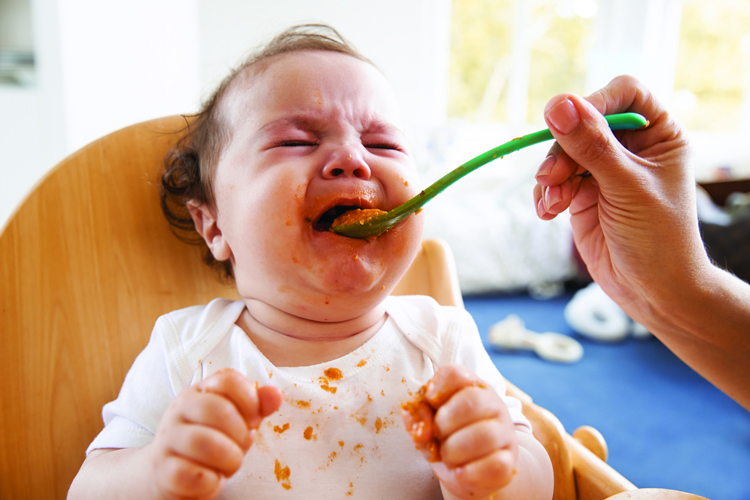 Toddler turning away from food on a plate